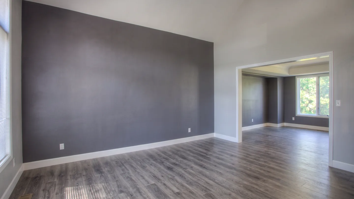 The same room with the furniture, art and rug removed, down to bare walls and floor
